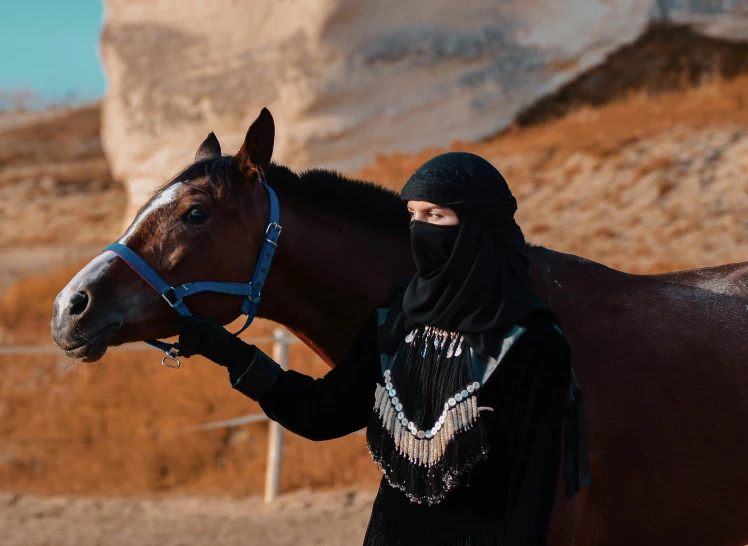 a girl poses with a horse next to a desert landscape