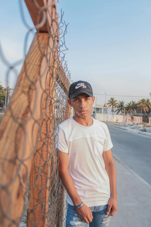 a young man leaning on the fence next to the road