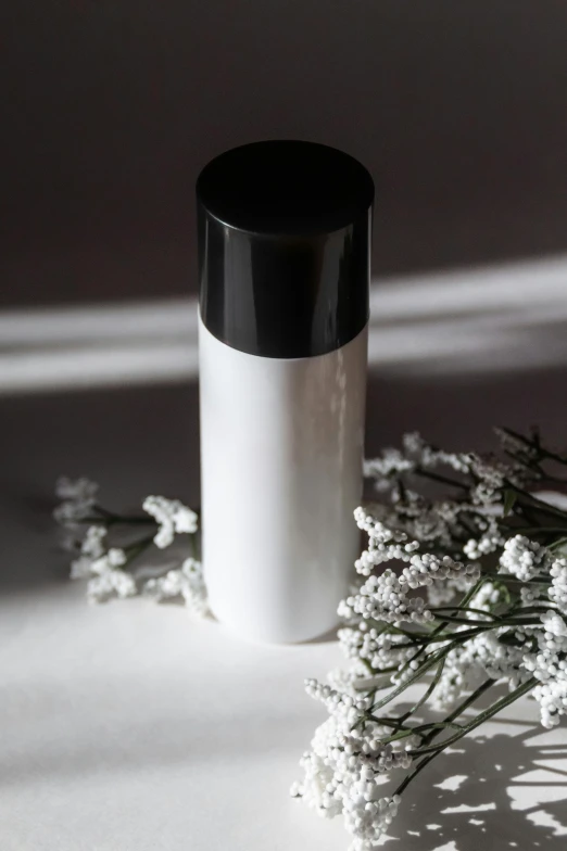 a white vase with some white flowers and leaves