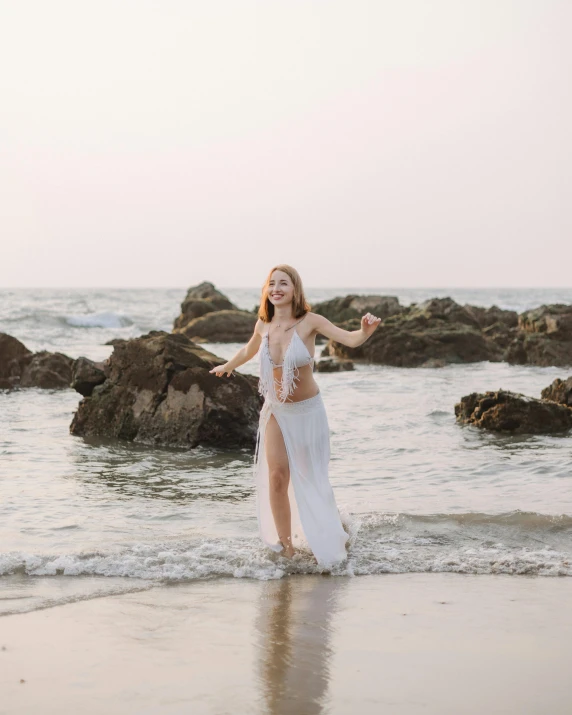 woman in white dress standing on ocean shore