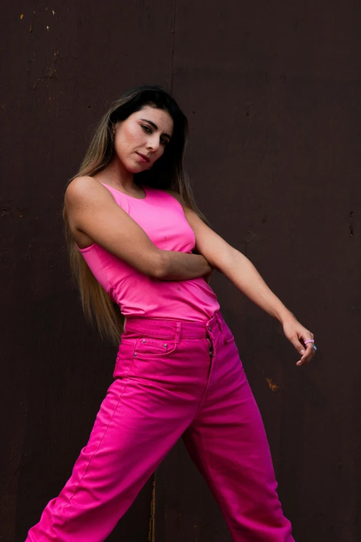 a woman in pink pants standing by a wall