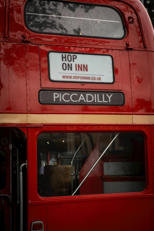 a red double - decker bus on the road with a sign for piccadilly