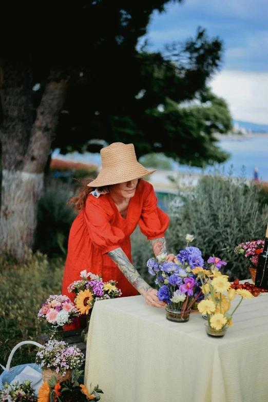 a woman sits behind a table with many flowers in her vases