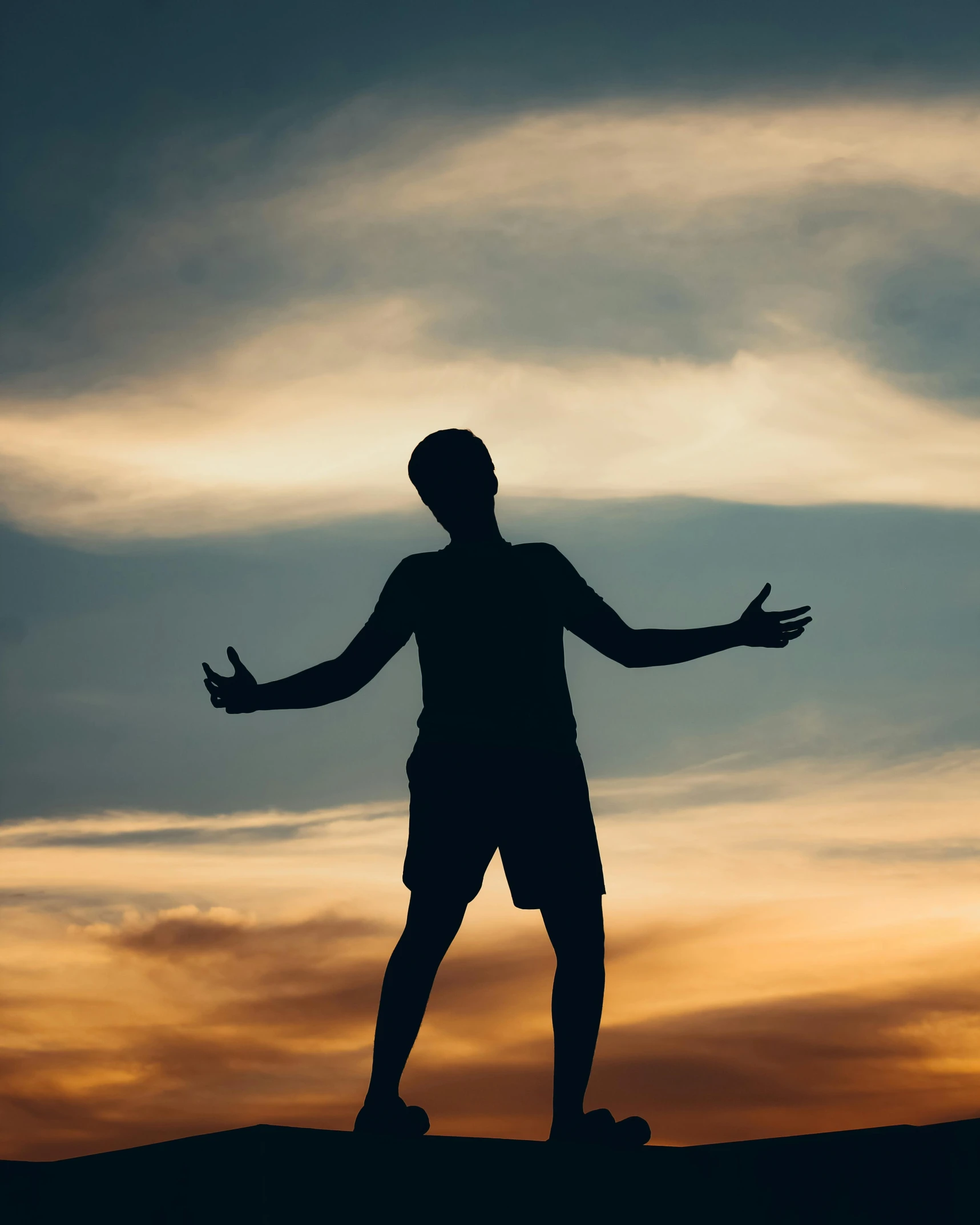 a silhouette of a man standing on top of a dirt hill