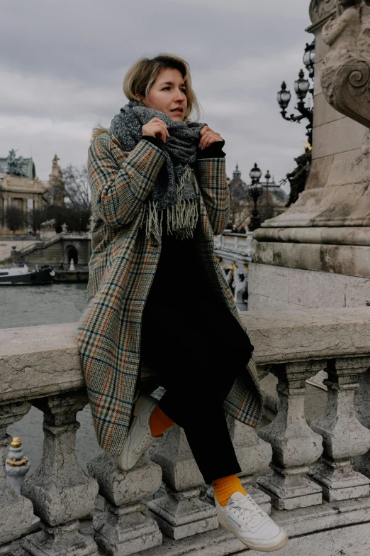 a woman in a coat poses on the bridge