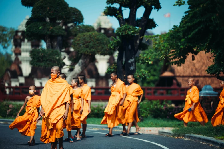 a group of monks walk down the street in orange robes