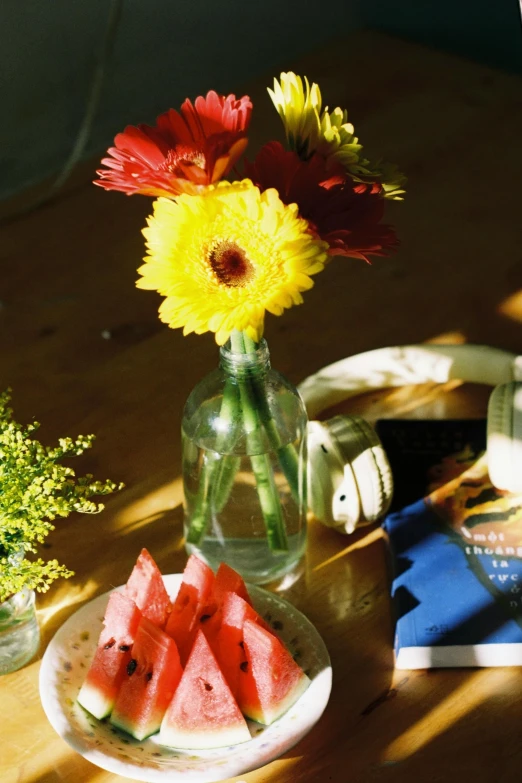 a watermelon plate topped with watermelon slices next to a vase with flowers