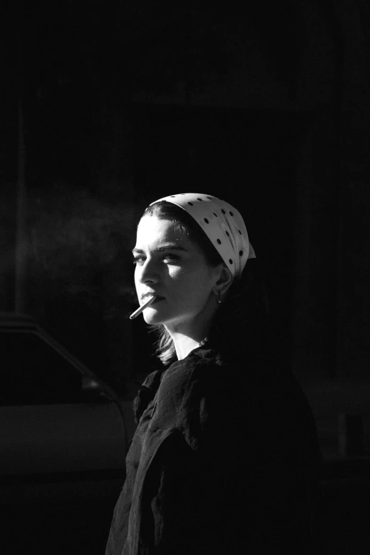 a woman with a bandana on her head smoking in the dark