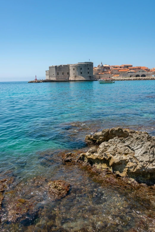 a rocky shoreline and island with a castle in the background