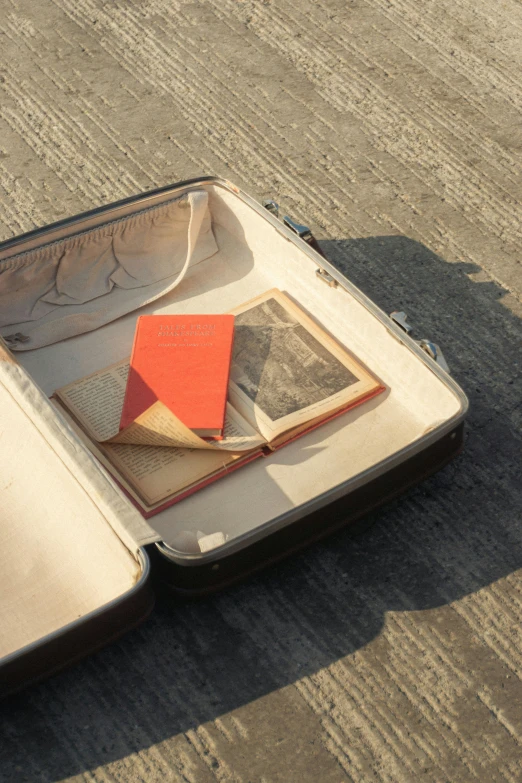 an open suitcase with a small orange book on the inside