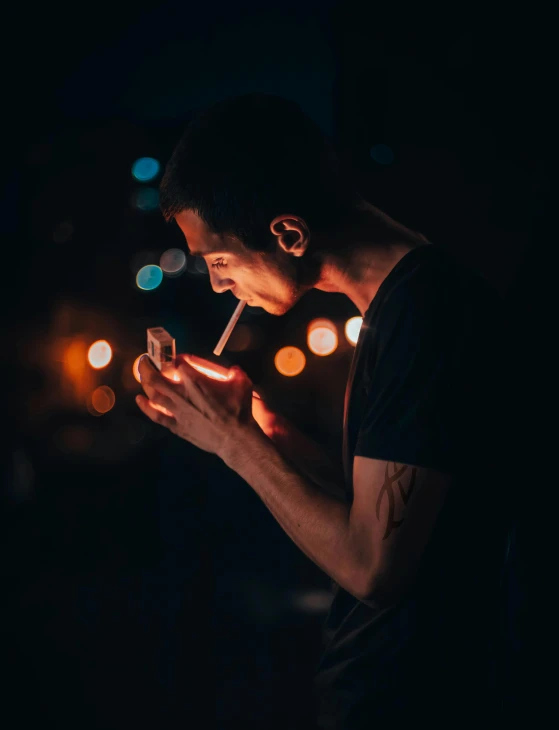 young man smoking a cigarette, with dark background