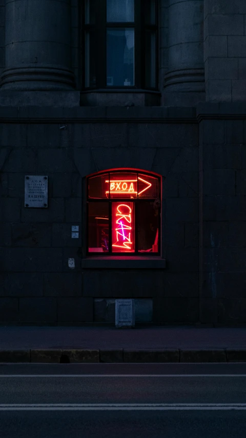 a neon sign on the corner of a dark building