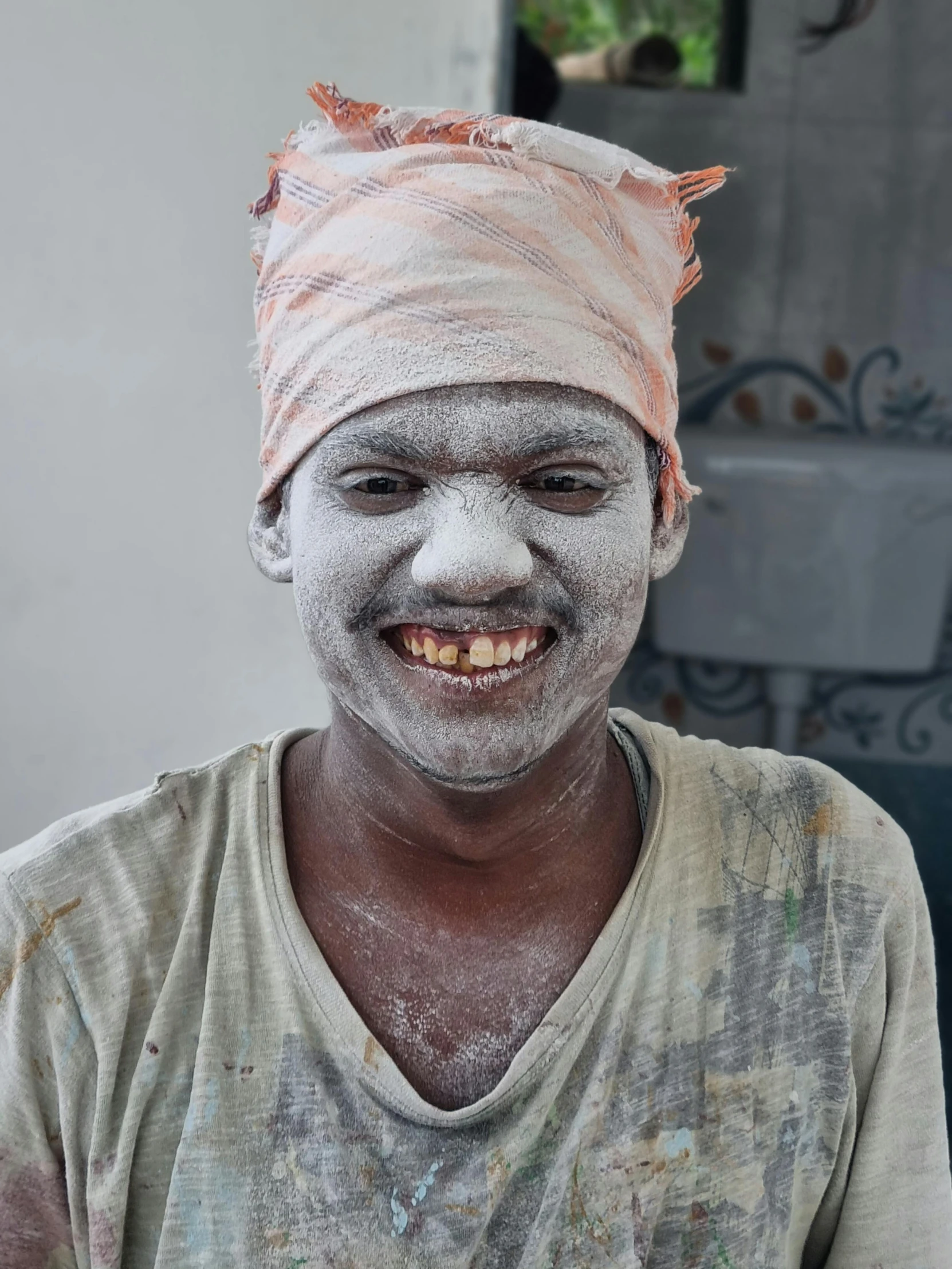 a man with painted face and hat, wearing a blanket