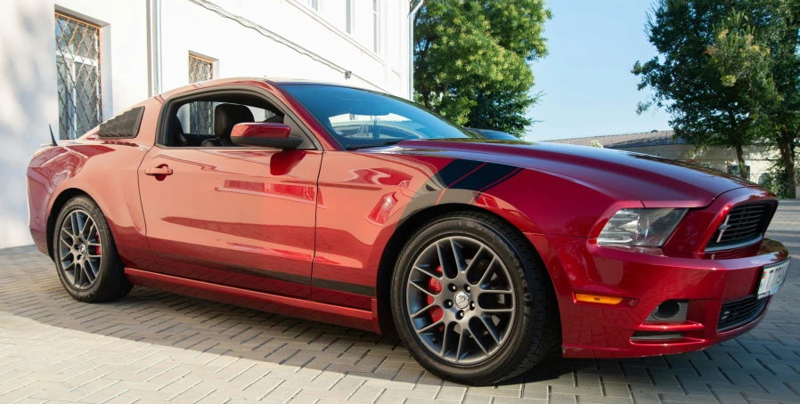 the side view of a red sports car parked in front of a building