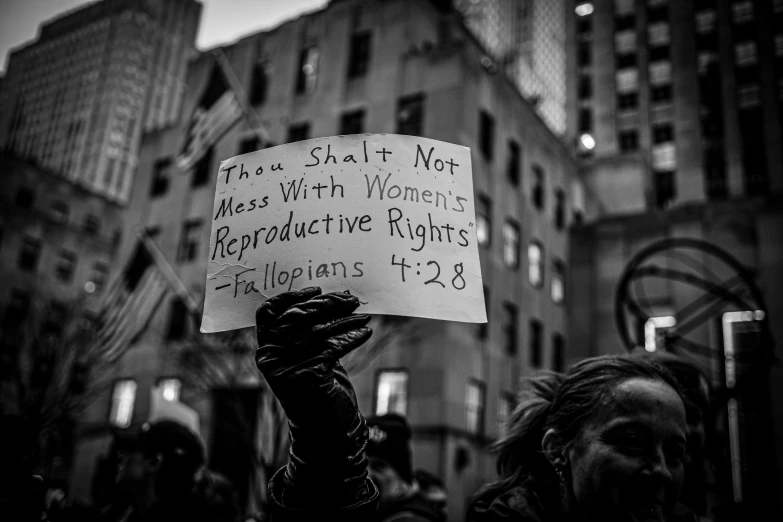 a person holding a sign that reads they shall not have birth women reproxivre rights