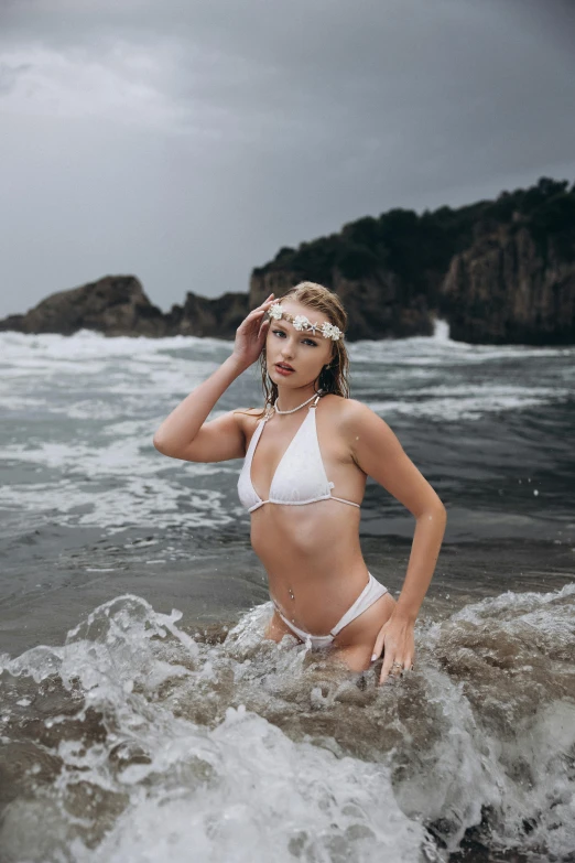 a young lady standing in the ocean at the beach