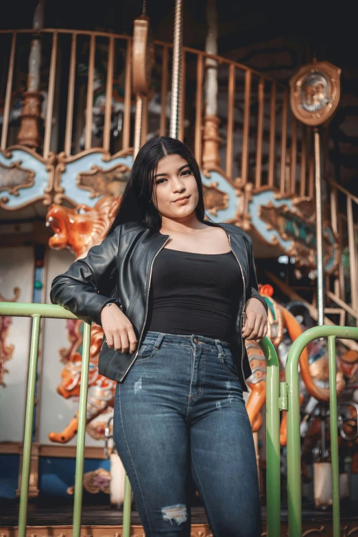 a beautiful woman with long black hair posing in front of an ornamental carousel