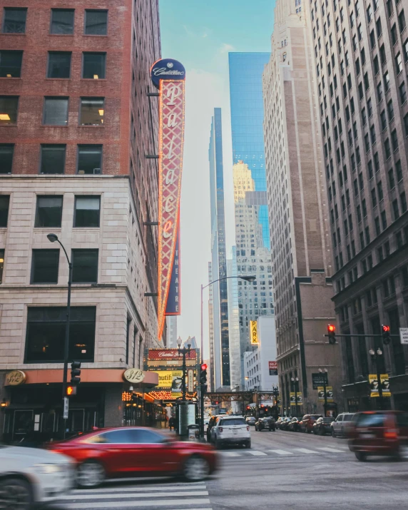 a city street filled with cars driving by tall buildings