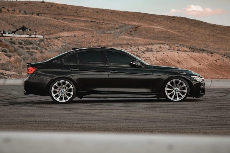 black car parked near a brown mountain on a cloudy day