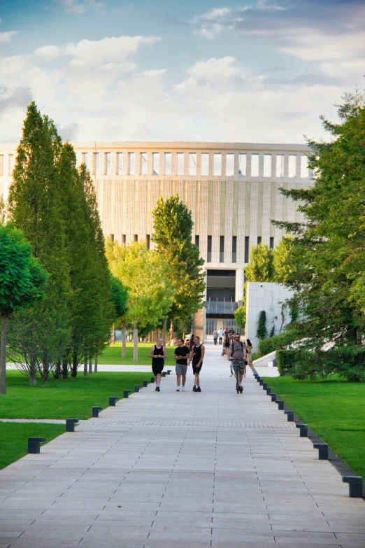 three people are walking down a walkway between two buildings