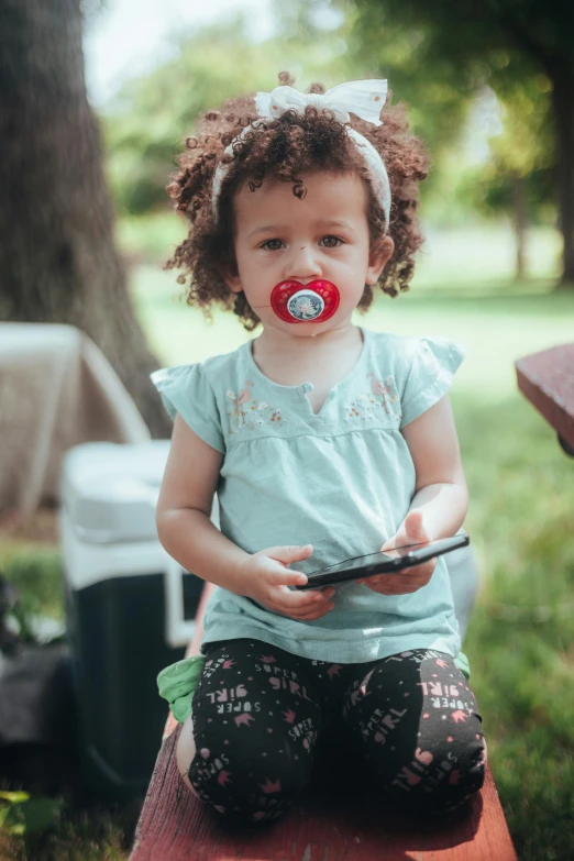 a baby girl with an open mouth sits on a bench