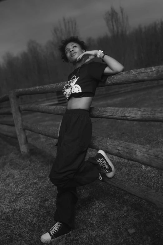 a young woman leaning on a wooden fence while wearing legging