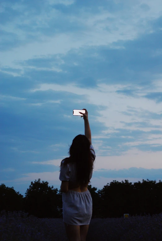 a girl is holding up her phone to the sky