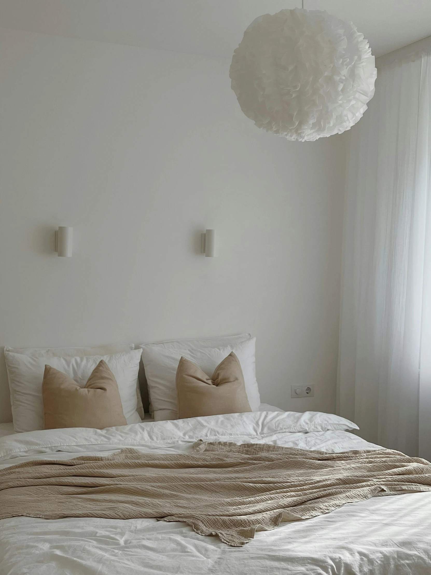 white bedding with fluffy pillows in an otherwise white bedroom