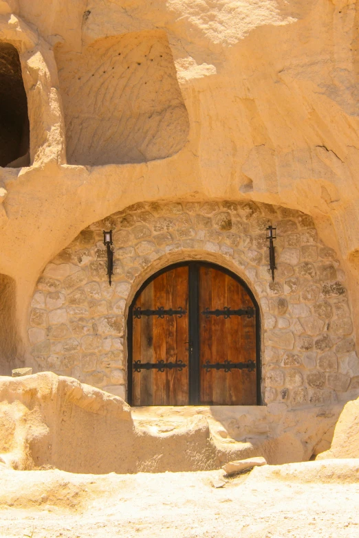 a rock building with two wooden doors to the other side