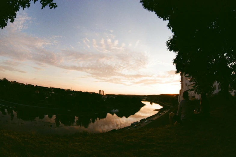 a river at sunset with the sun peeking through trees