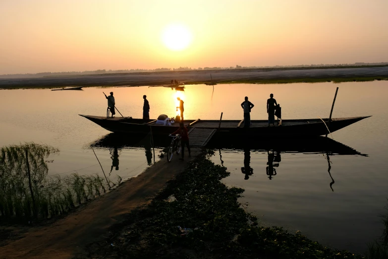 people standing on boats in the water during sunset