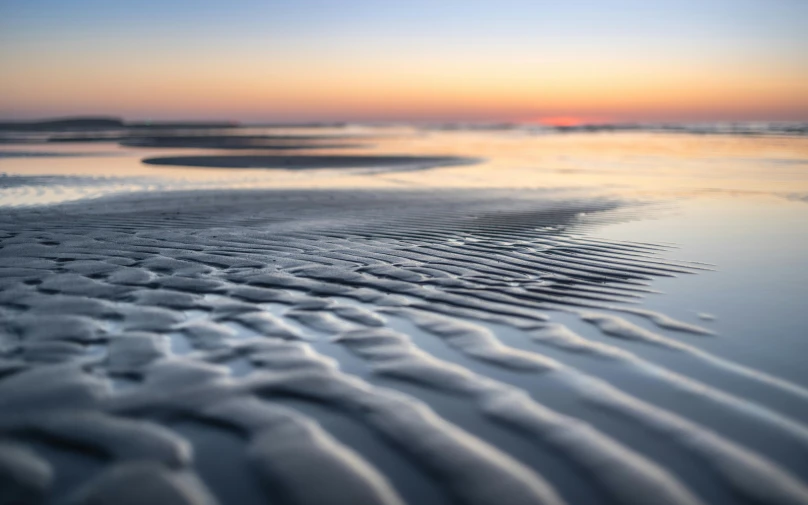 a wet sandy beach next to a body of water