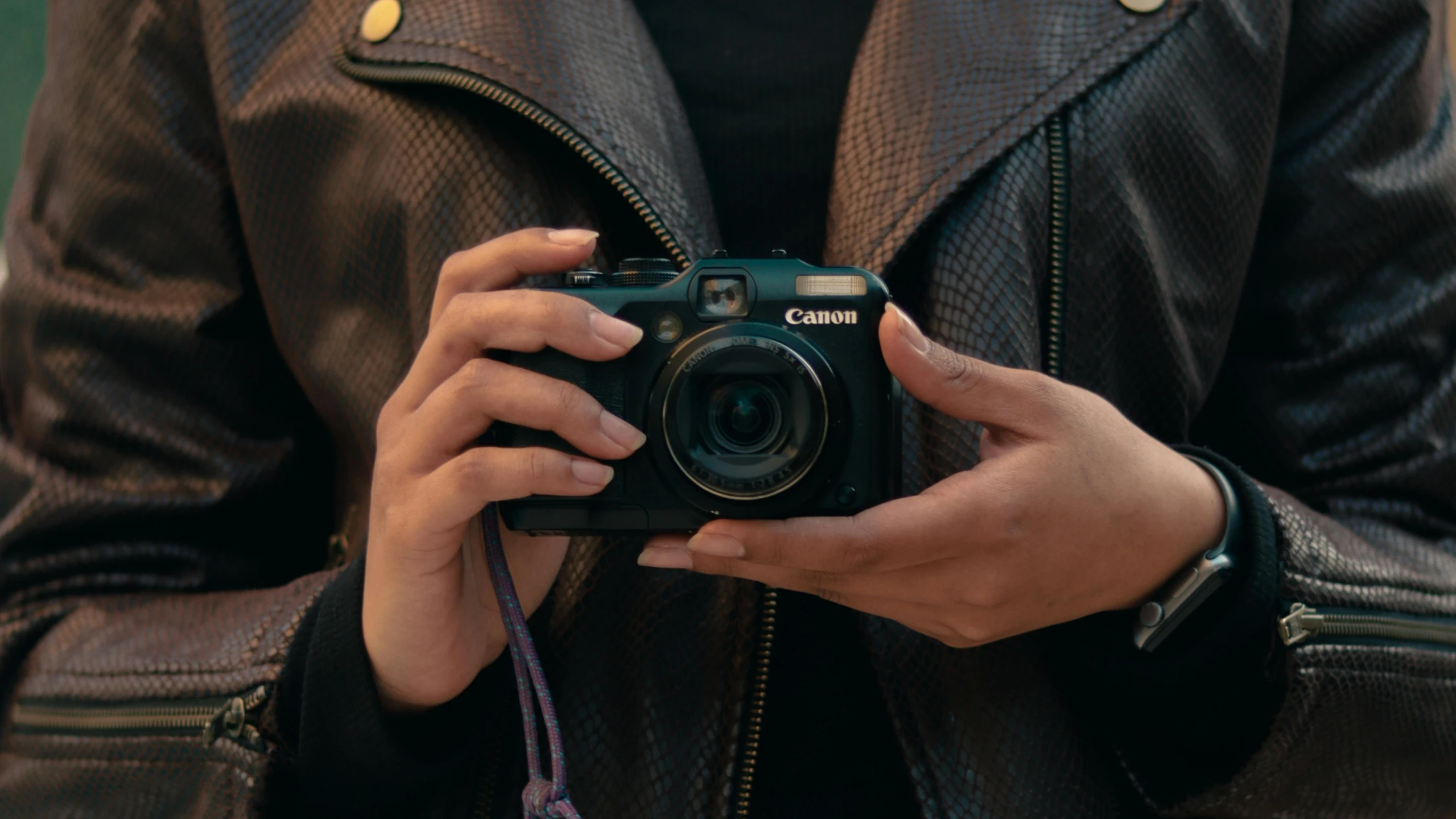 a person holding a camera and wearing a leather jacket