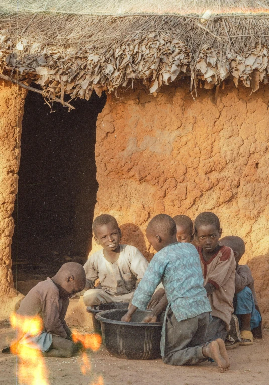 a group of s standing outside of a mud hut