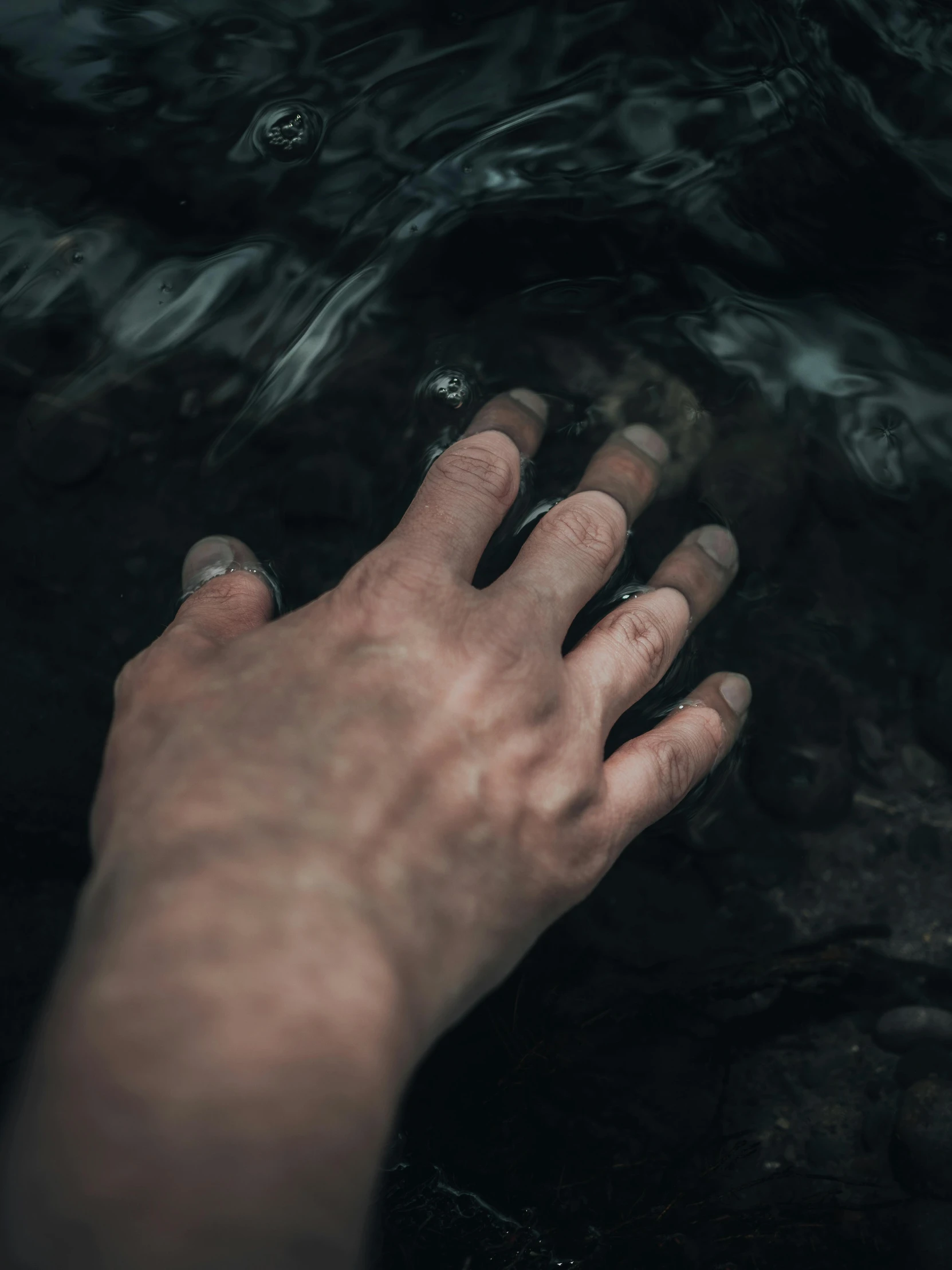 a person's hand with their left hand extended up under water