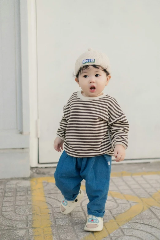 the baby is wearing a baseball cap and blue pants