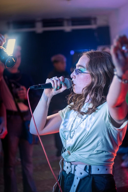 a young woman singing into microphone in front of the crowd