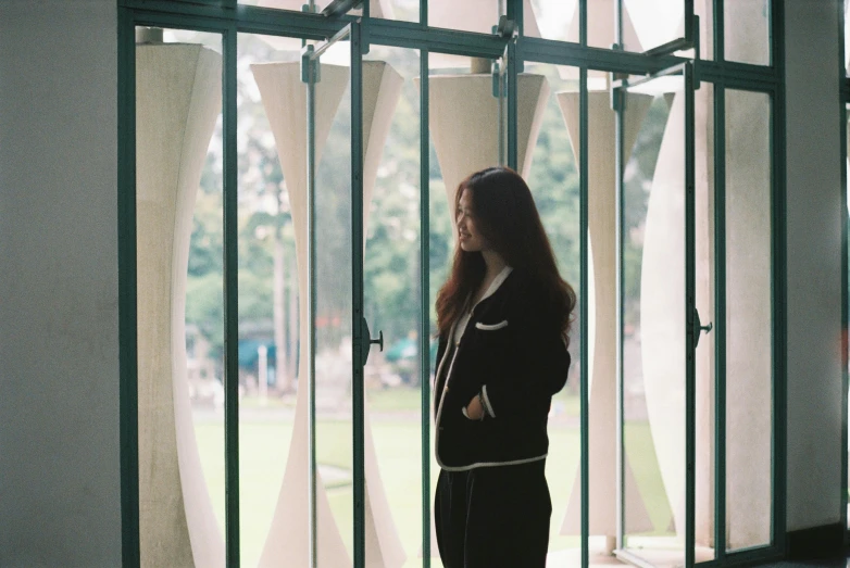 there is a young woman standing by the glass windows