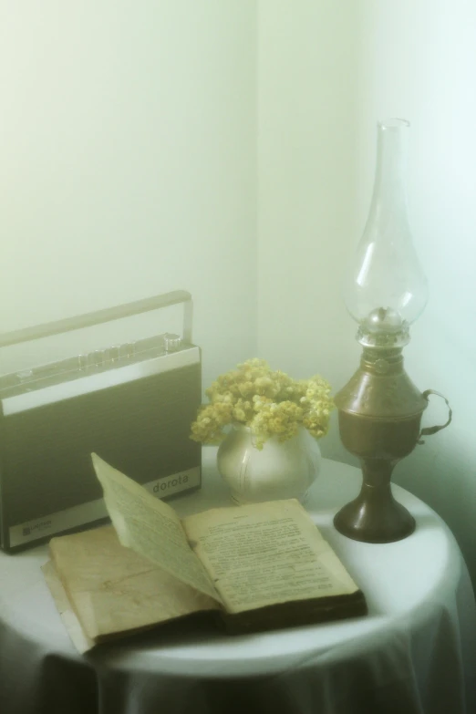 the table is cluttered with an antique book, old radio, and a vase with yellow flowers