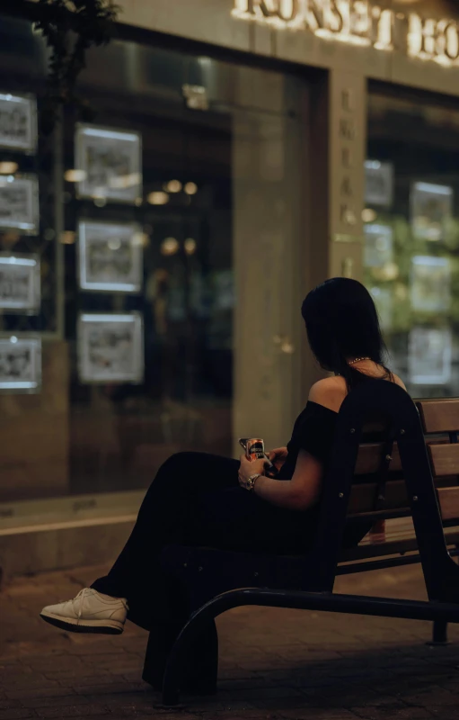 a woman sitting on a park bench looking at her cell phone