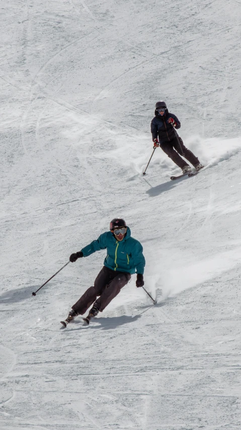 a couple of people riding skis down a snow covered slope