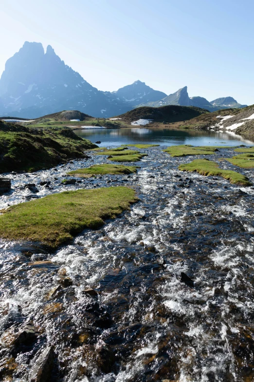 a river flows between two mountains that have grass growing