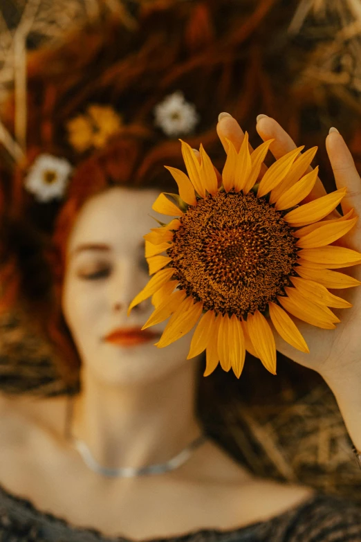 woman with sunflower in hair, covering face