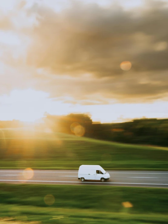 the van is driving down the road in the evening sun