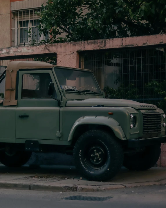 an army green military truck parked next to a building
