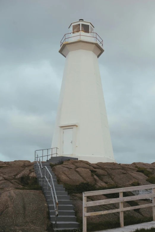 a white light house sitting on top of a rocky hill