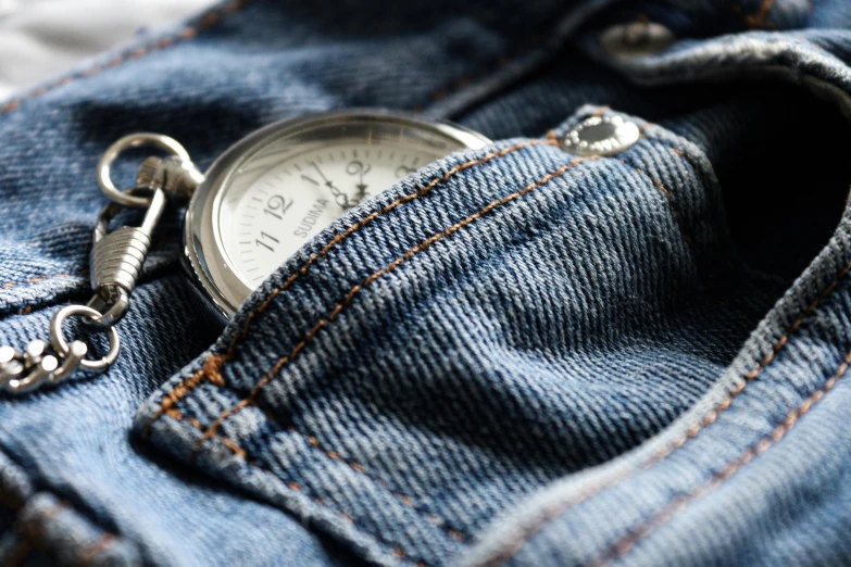 an old pocket watch on a pair of blue jean pants