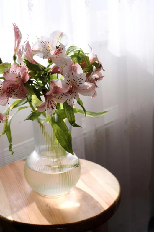 a clear vase with pink flowers on a table