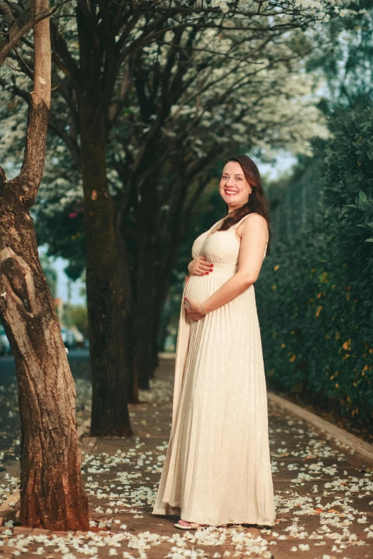 a pregnant woman standing under a tree in the woods