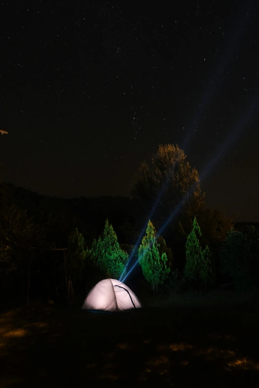 a camping tent in the middle of night with a light shining on it